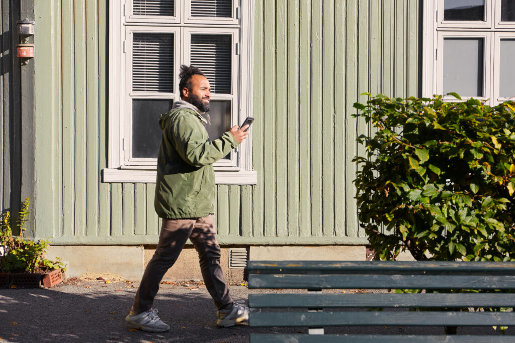 Smilende mann gående i solen og leser en RCS